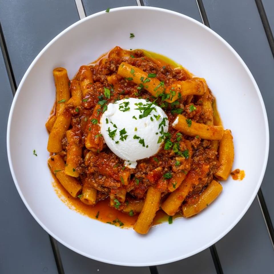 Fratelli By Jholano's rigatoni pasta with rich bolognese sauce, topped with a dollop of fresh ricotta.