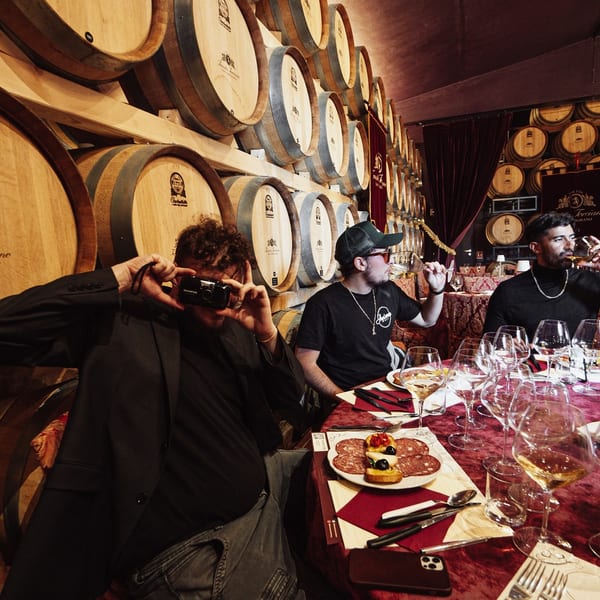 Three men enjoying wine and charcuterie at a table surrounded by wine barrels at Fratelli By Jholano's.