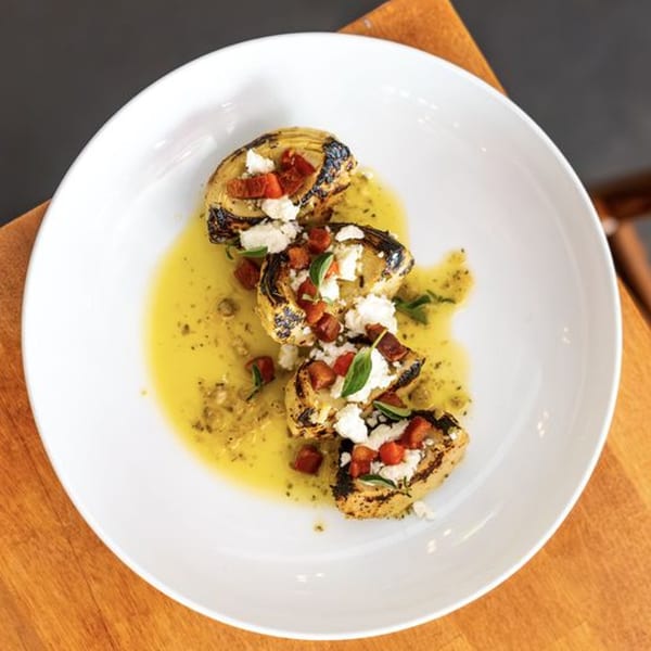 Grilled artichoke hearts with crumbled feta, diced tomatoes, and fresh basil in a lemon-herb sauce.